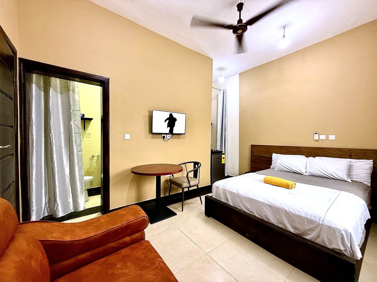 Queen studio suite with queen size bed, AC, sofa, table and TV