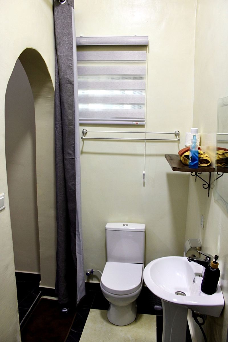 Queen studio suite bathroom with toilet, sink and shower curtain